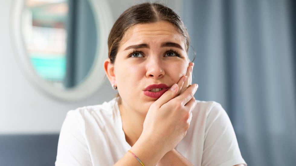 A woman holding her cheek due to severe toothache pain, requiring urgent care from a St. Marys emergency dentist.
